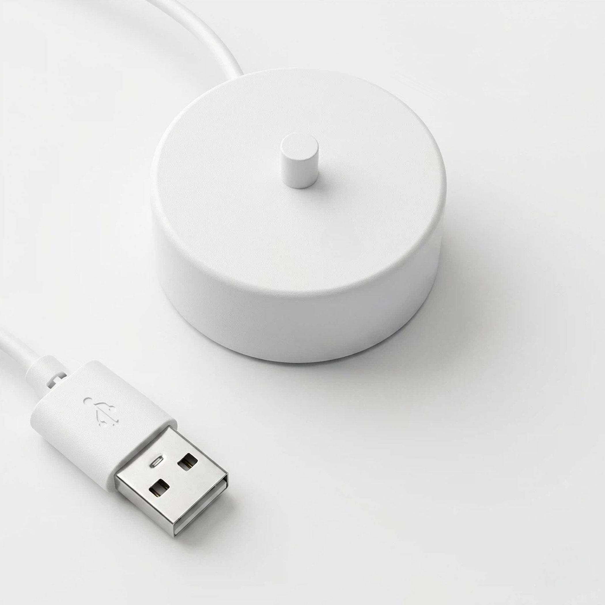 Ein weißes USB-Ladekabel und eine Basis auf weißem Hintergrund.