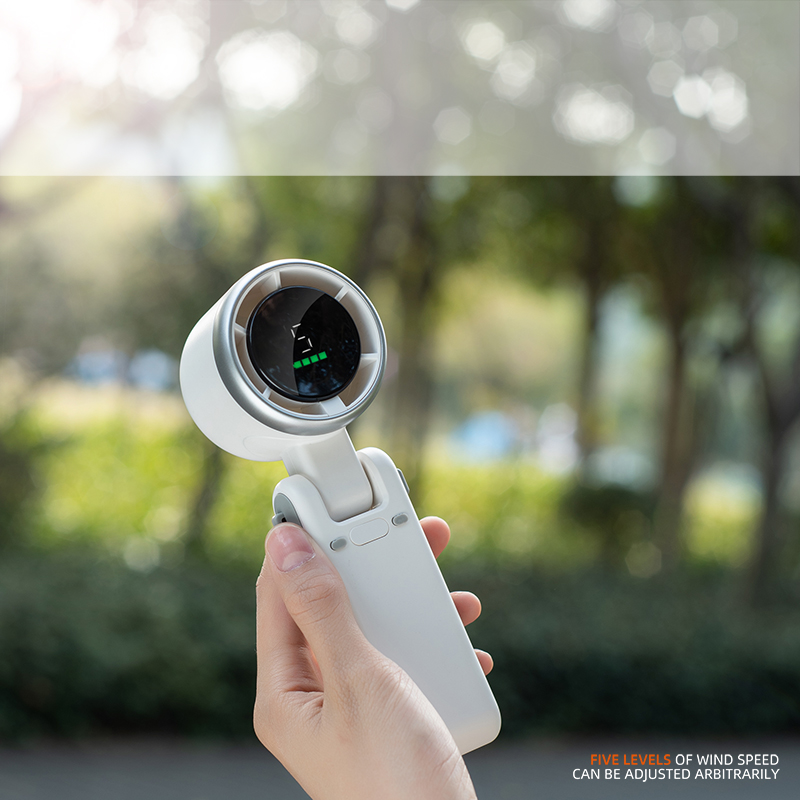 Eine Hand hält einen weißen Ventilator mit grünem Balken-Display im Freien.