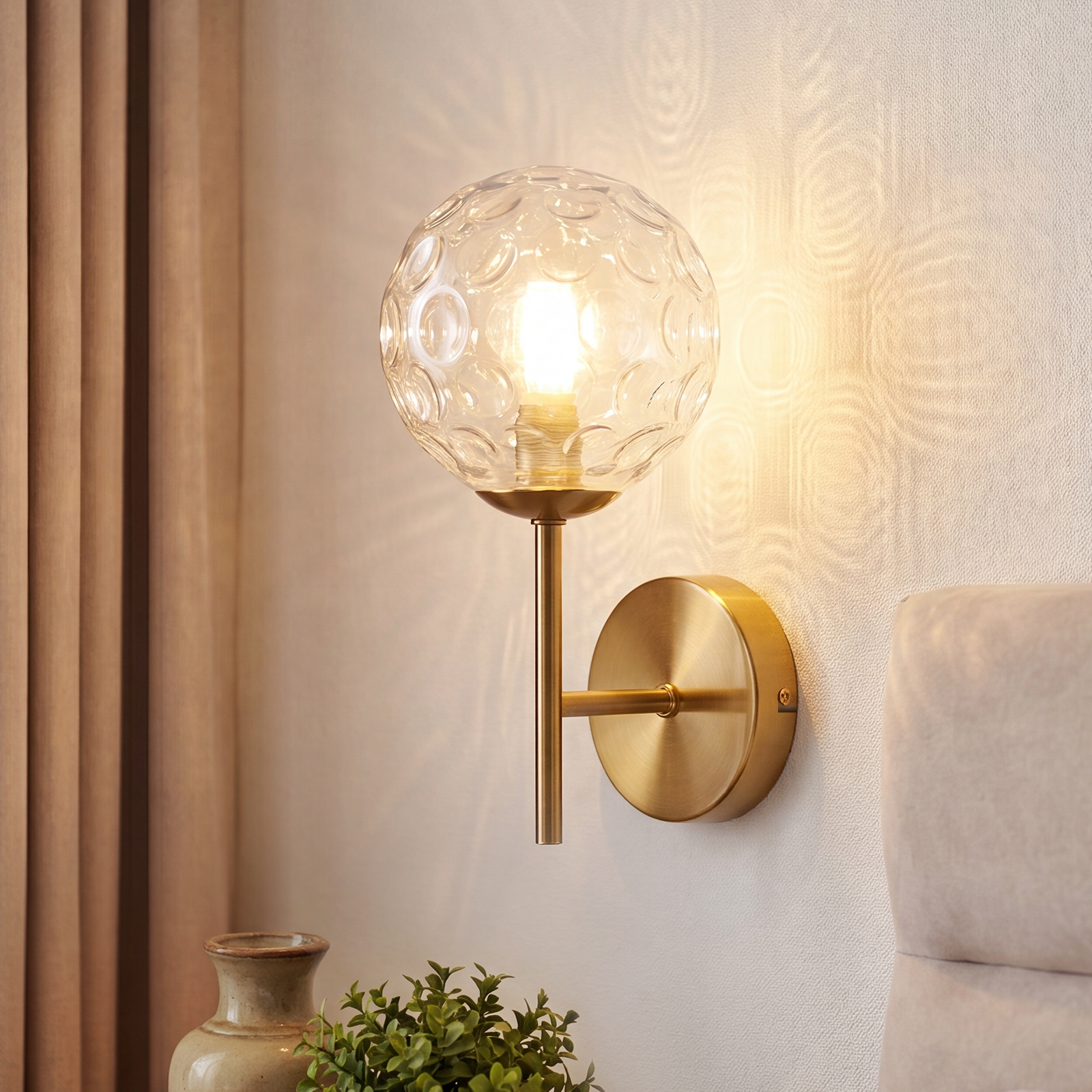 Mosiężna lampa ścienna ze sferycznym szklanym kloszem z wzorem bąbelków.