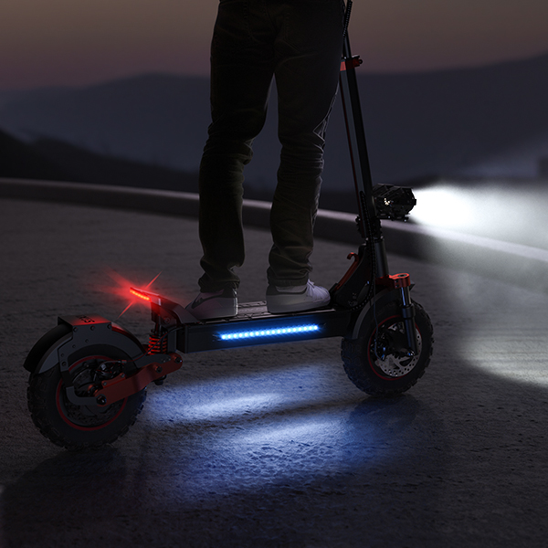 Una persona sta su un monopattino elettrico con luci blu e rosse di notte.