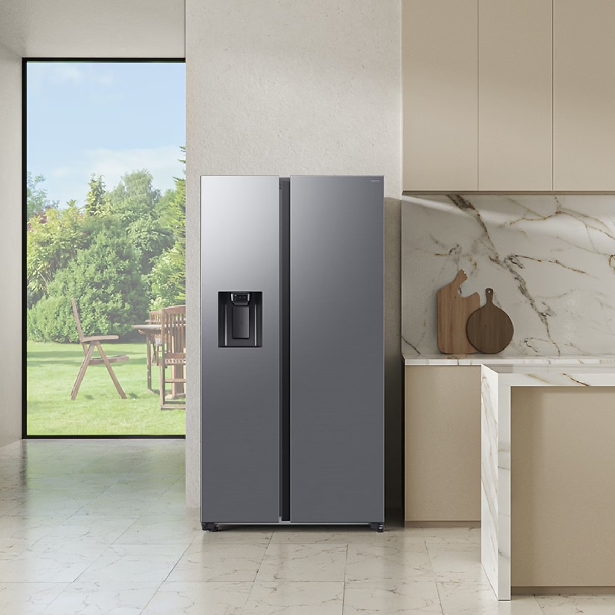 Ein moderner grauer Kühlschrank mit Wasserspender steht in einer Küche mit Blick auf einen Garten.