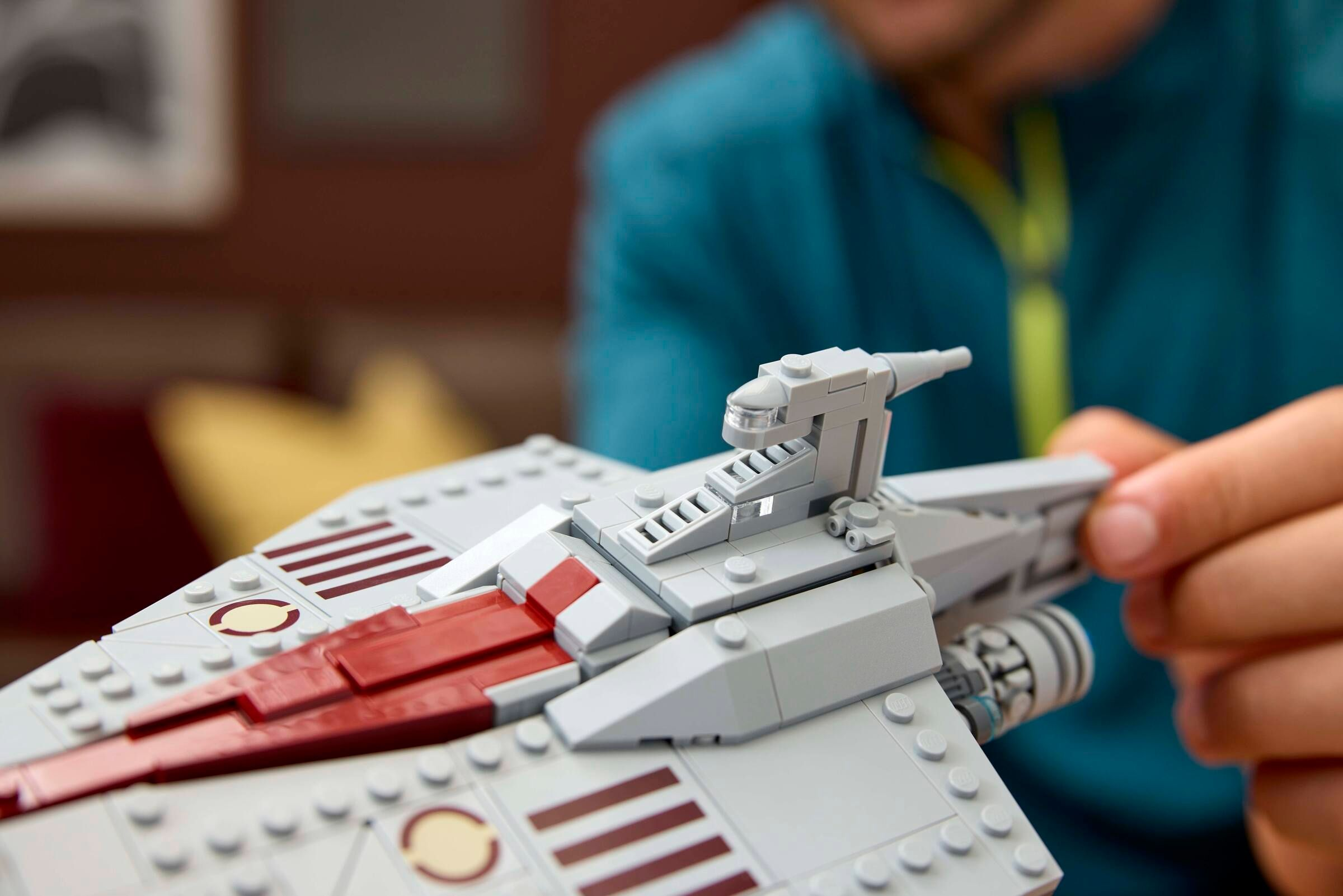 Graues Lego-Raumschiff mit roten Akzenten, das von einer Hand gehalten wird.