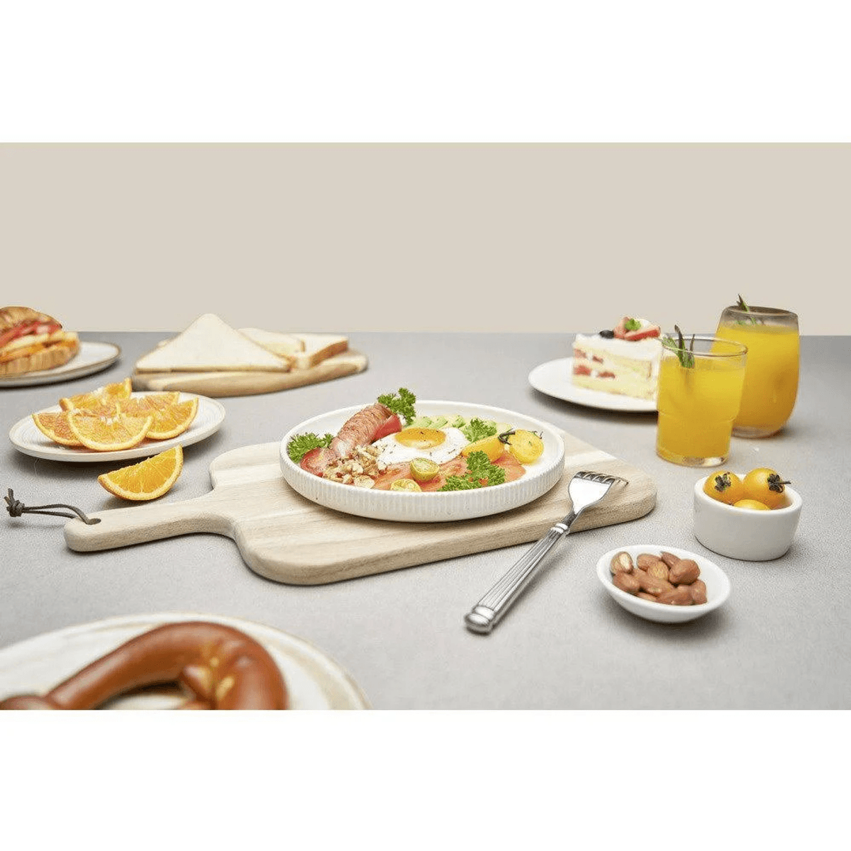 Desayuno con huevos, tocino, naranjas, pastel, jugo y bollería.