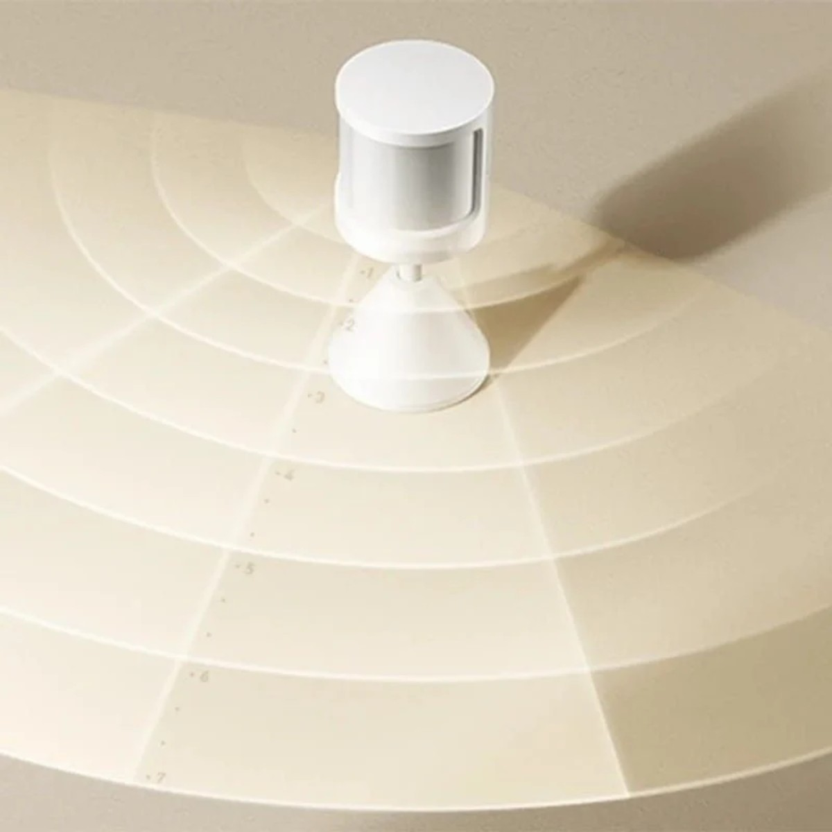 Un sensor de movimiento blanco con base cónica sobre superficie crema con círculos concéntricos.