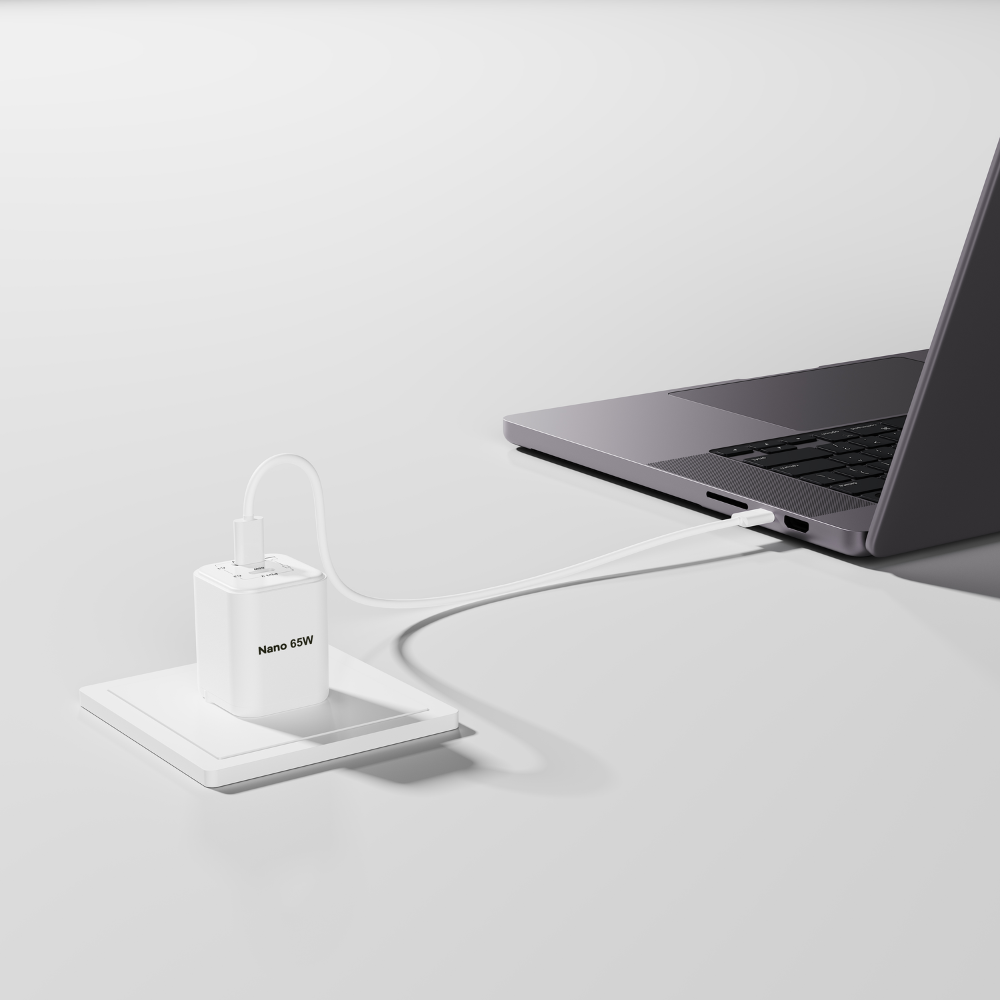 Ein weißer 65W Ladeadapter lädt einen Laptop über ein weißes Kabel.