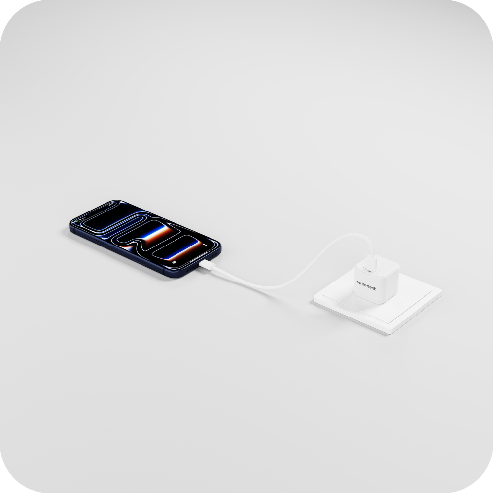 Ein dunkelblaues iPhone lädt an einem weißen Adapter in einer weißen Steckdose.