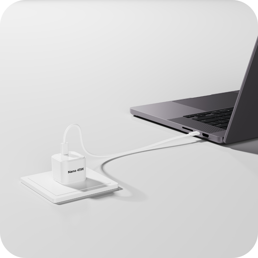 Ein weißer 45W Netzstecker lädt einen grauen Laptop über ein weißes Kabel.