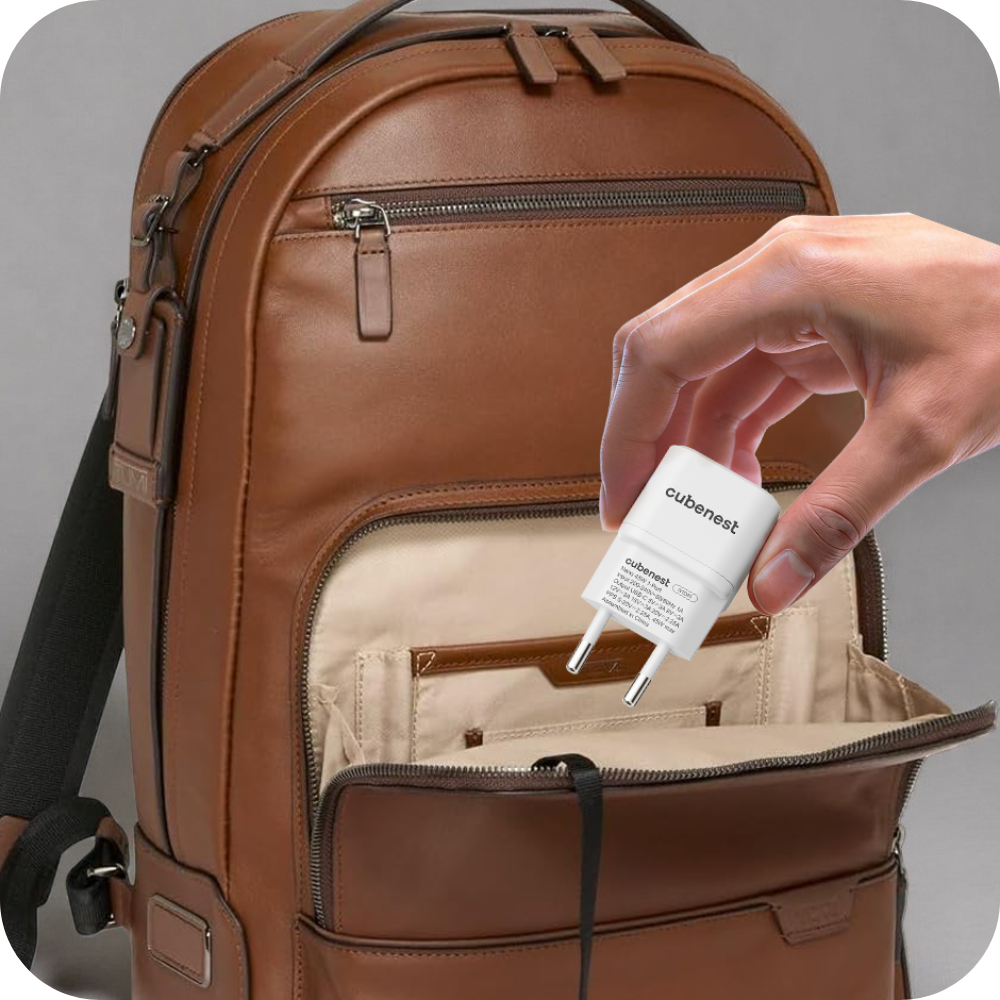 Eine Hand hält einen weißen Cubenest-Ladestecker über eine geöffnete braune Ledertasche.