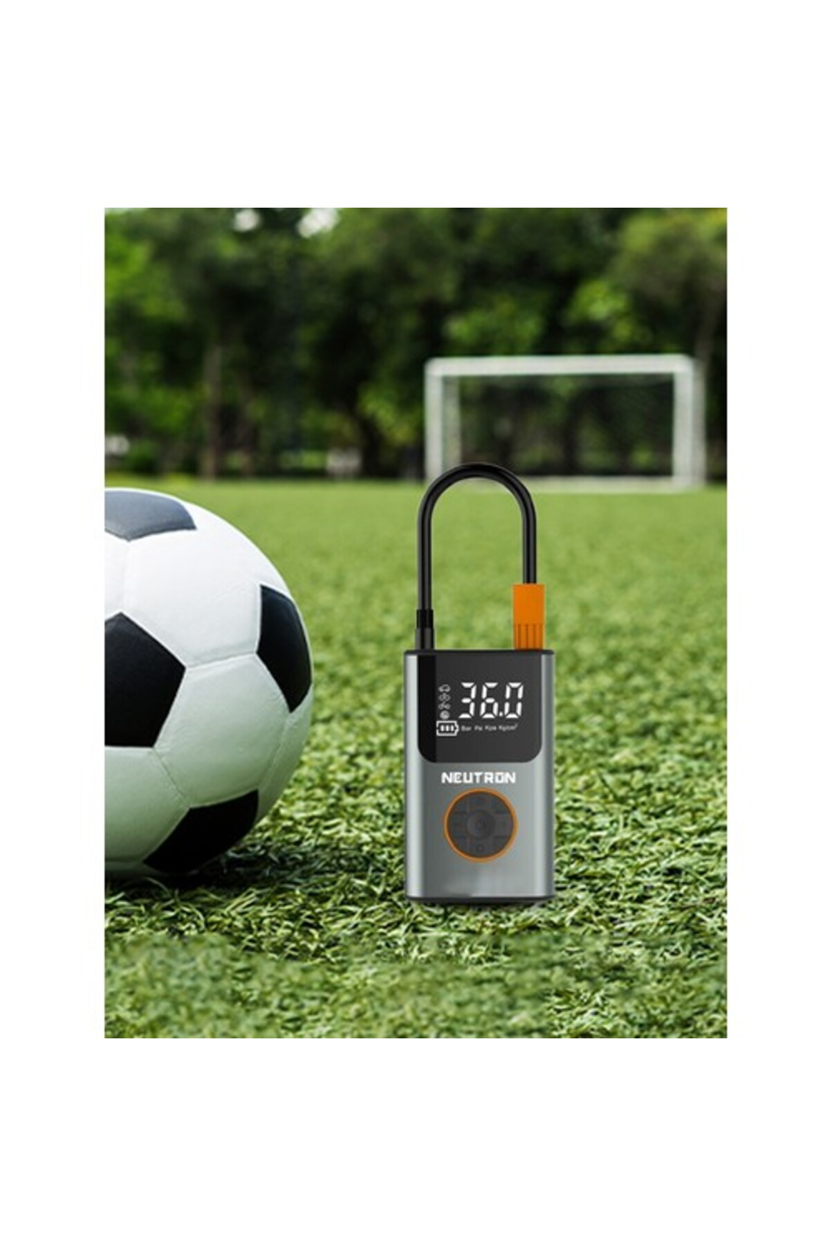 Futbol topu ve hava pompası suni çimde, kale yakınında duruyor.