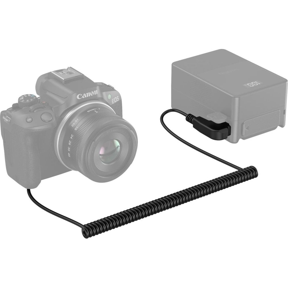 Grijze camera met lens en zwarte kabel aangesloten op een stroomvoorziening.