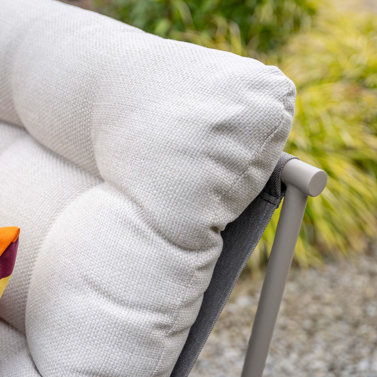 A beige cushion on a gray chair with a green background.