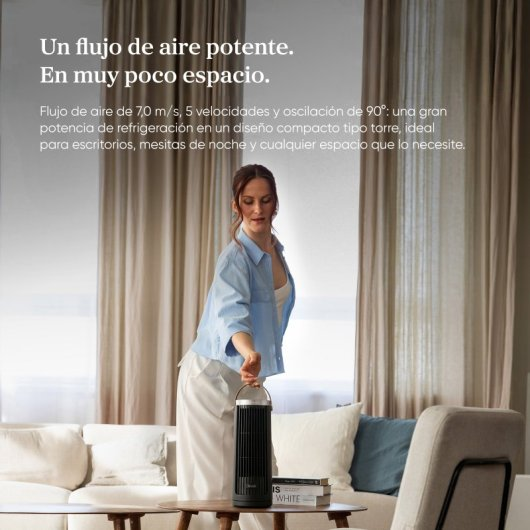Una donna tiene un'elegante ventola a torre nera in un soggiorno.