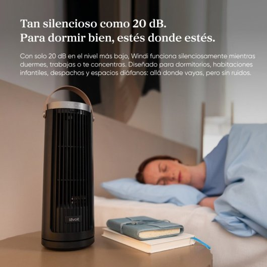 Una ventola a torre nera si trova accanto a un letto dove dorme una donna.