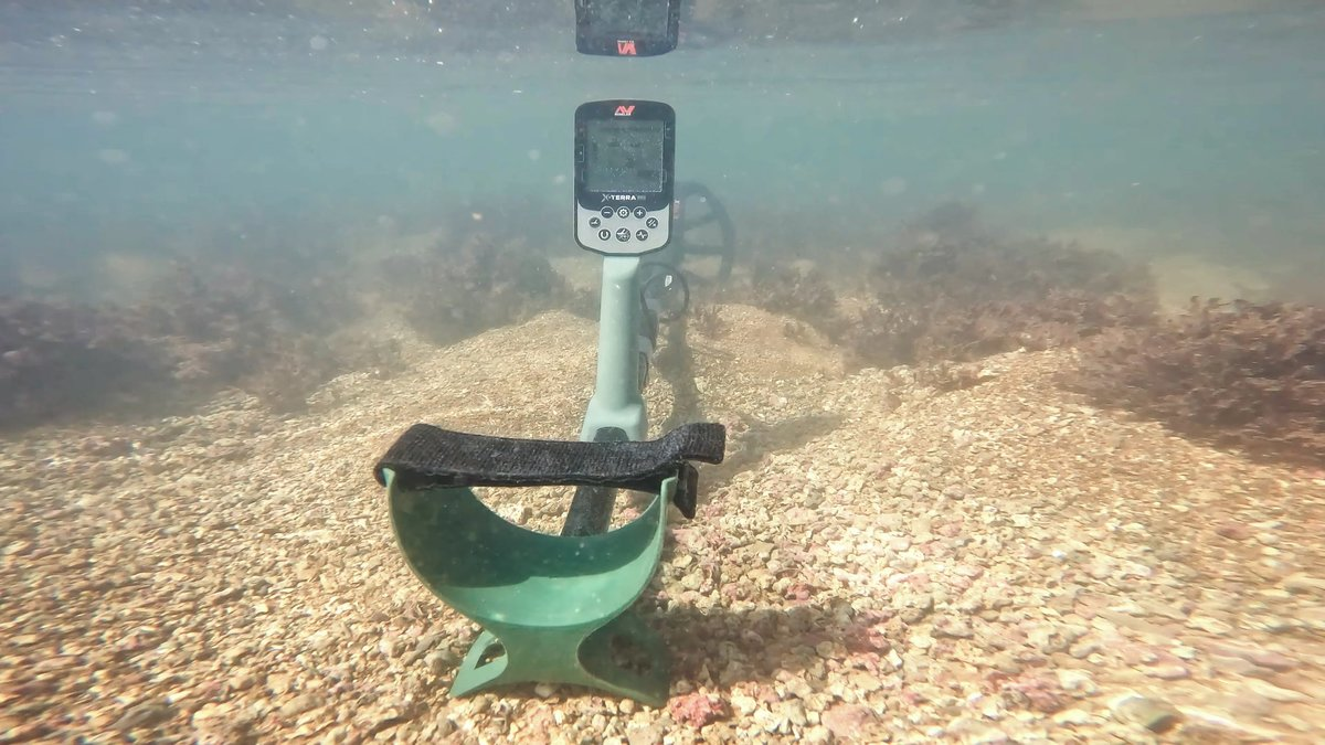 Ein Metalldetektor liegt unter Wasser auf einem steinigen Grund.