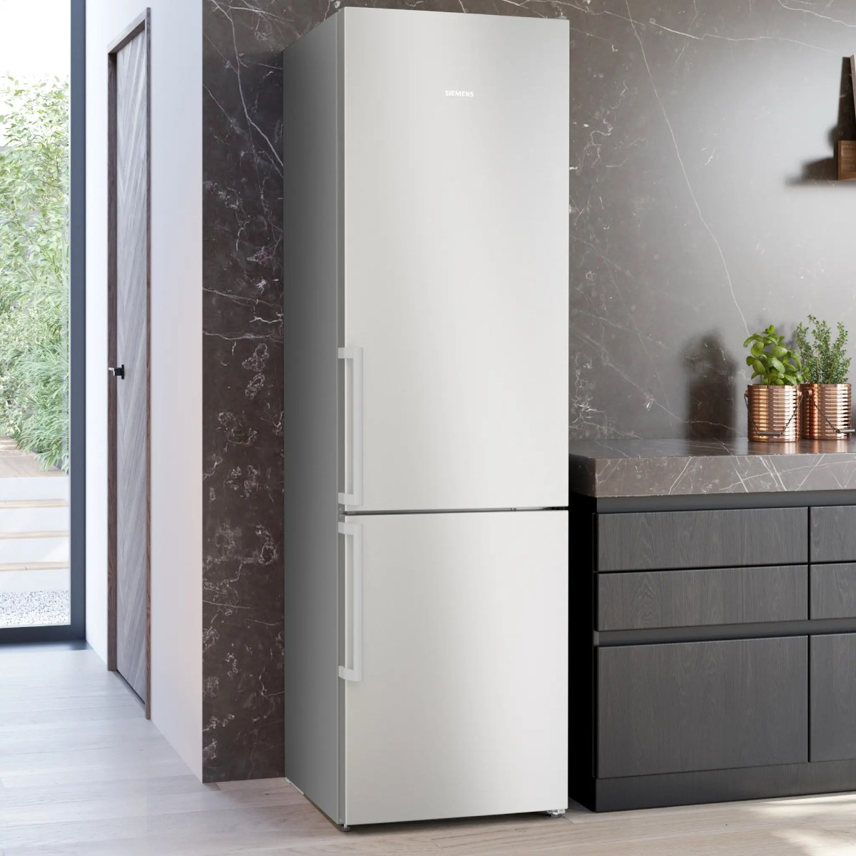 Un frigorifero bianco Siemens accanto ad armadi scuri in una cucina moderna.