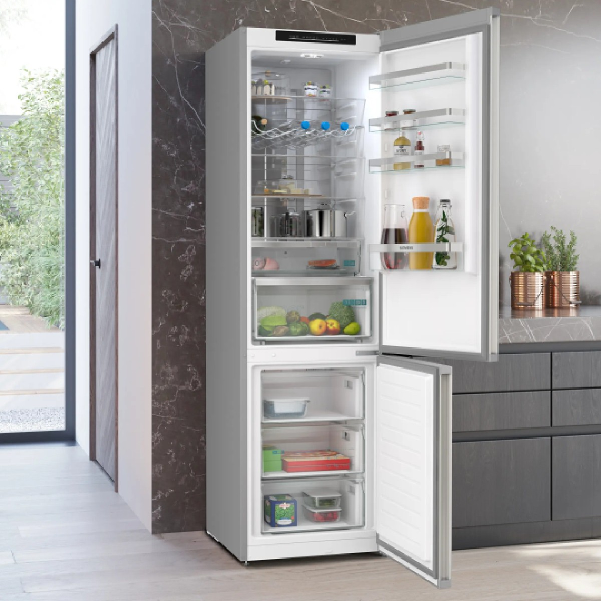 Offener weißer Kühlschrank mit Lebensmitteln und Schubladen in einer modernen Küche.
