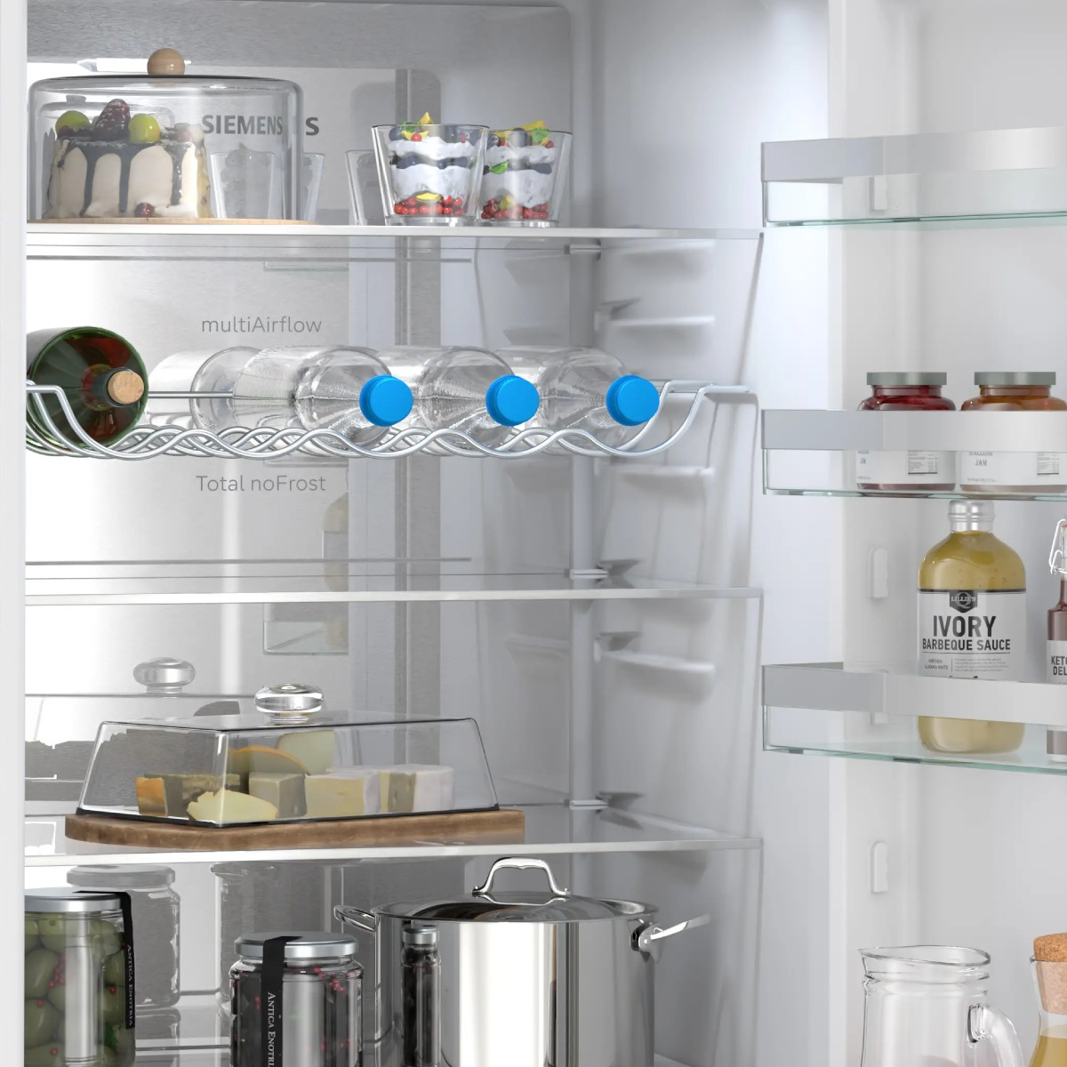Interior de refrigerador: pastel, postres, botellas, queso, ollas y frascos.