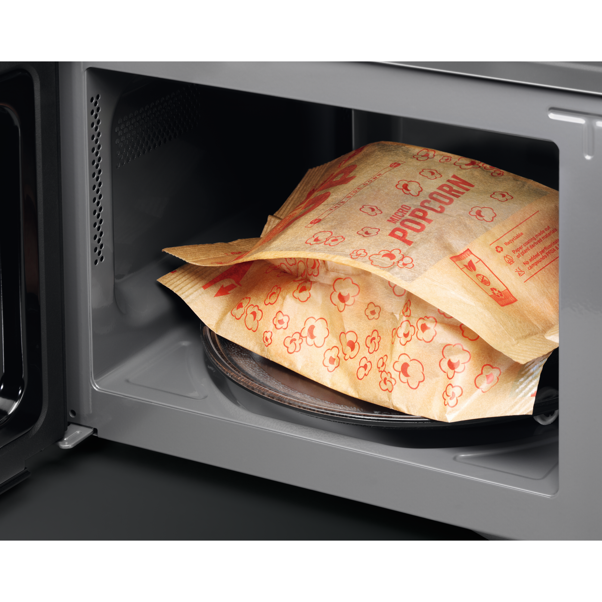 Eine Tüte Mikrowellen-Popcorn mit roten Designs liegt in einer Mikrowelle.