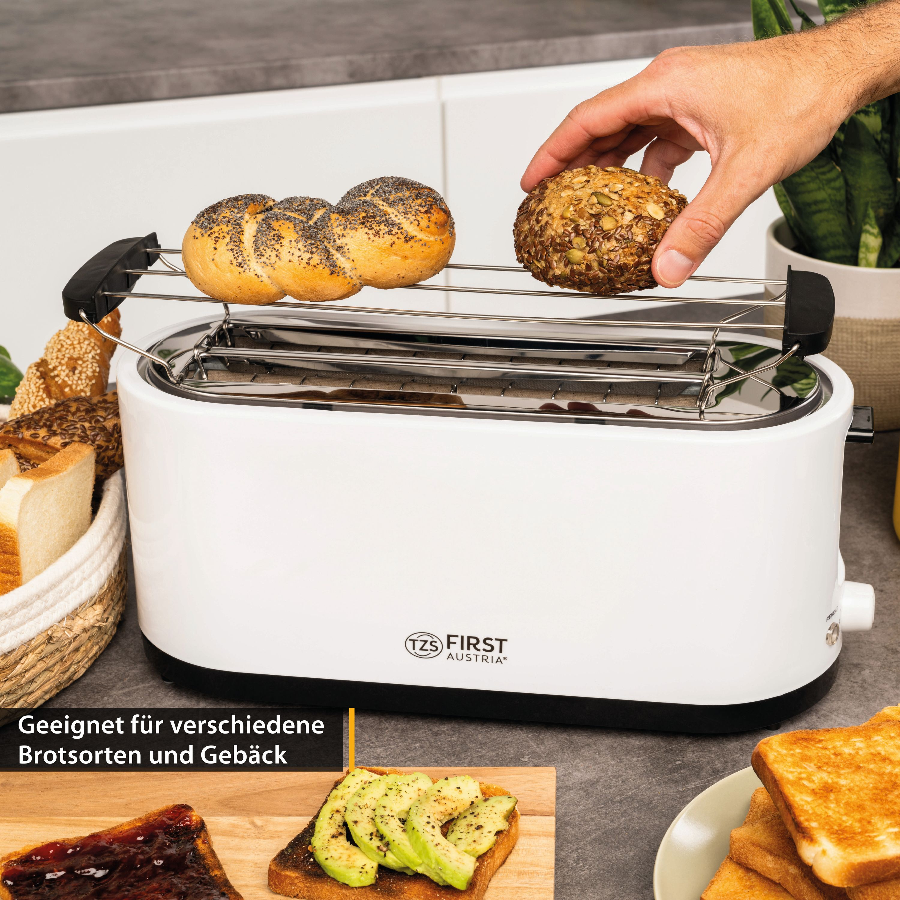 Ein weißer Toaster mit Brötchen auf dem Rost. Ein Arm legt ein Brötchen hinein.