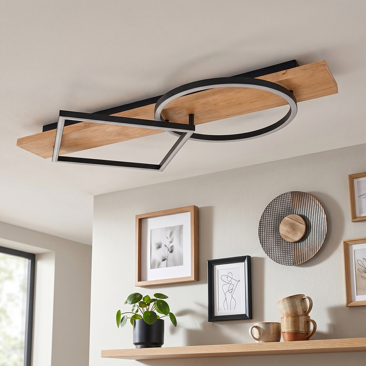 Moderne Deckenleuchte mit Holz und Metallformen, gerahmte Bilder und Pflanzen an der Wand.
