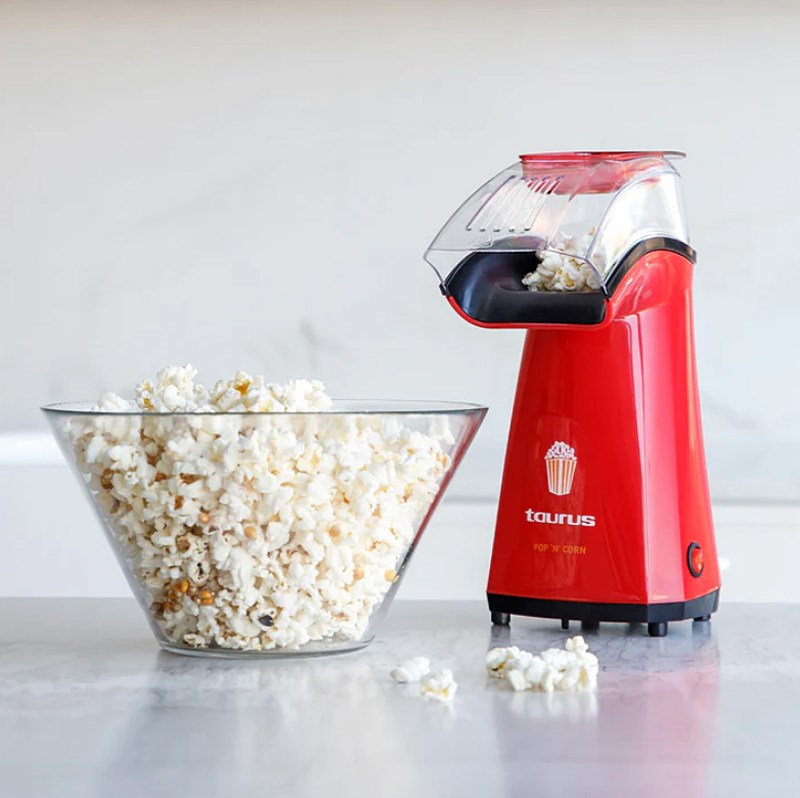 Rote Popcornmaschine mit Schüssel voller Popcorn auf Marmortheke.