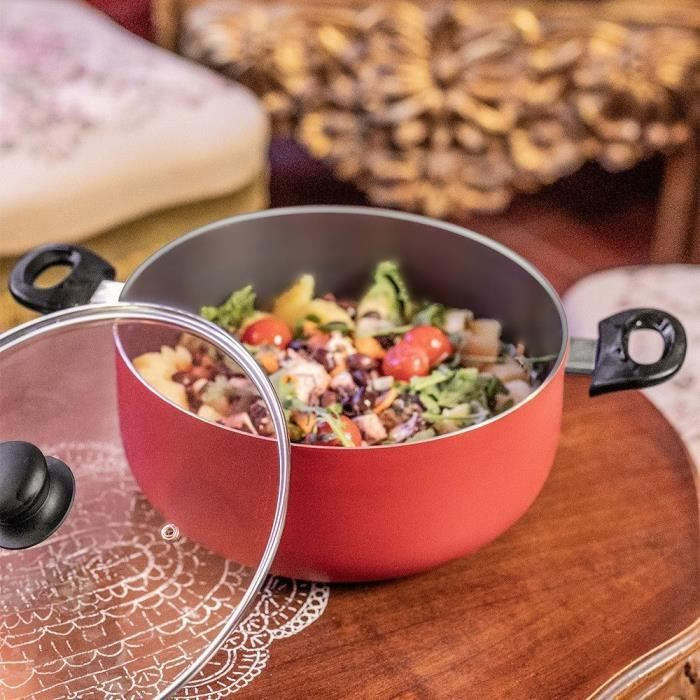 Olla roja con ensalada, tomates cherry y hojas de lechuga sobre mesa madera.