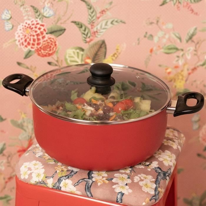 Una olla roja con tapa, llena de ensalada, se asienta sobre un taburete estampado.