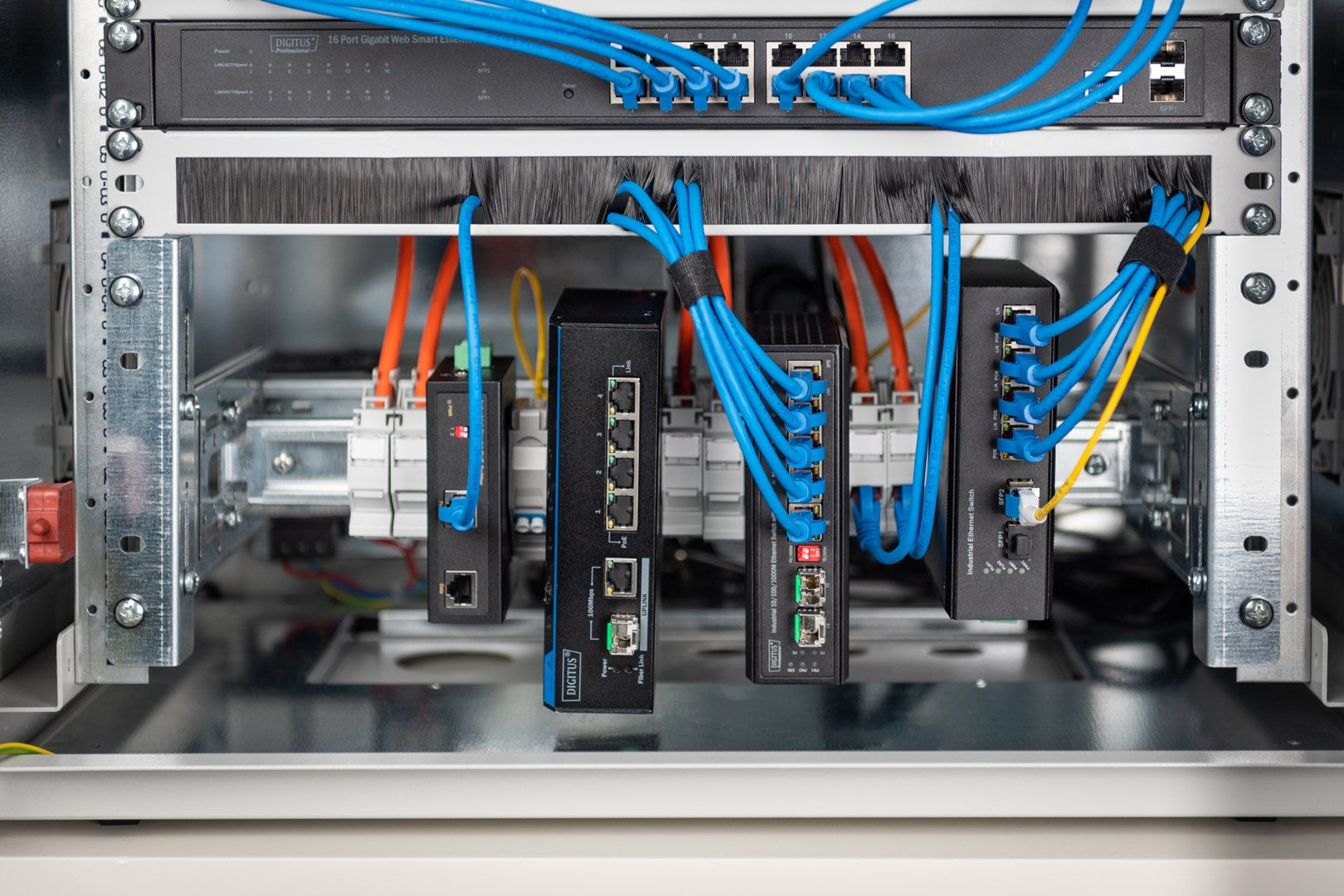 Netzwerkschrank mit Switches, Routern und blauen Kabeln.