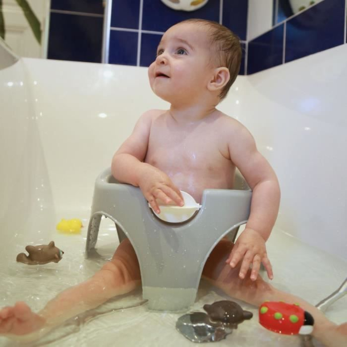 Bebé en asiento de baño gris en la bañera con juguetes.