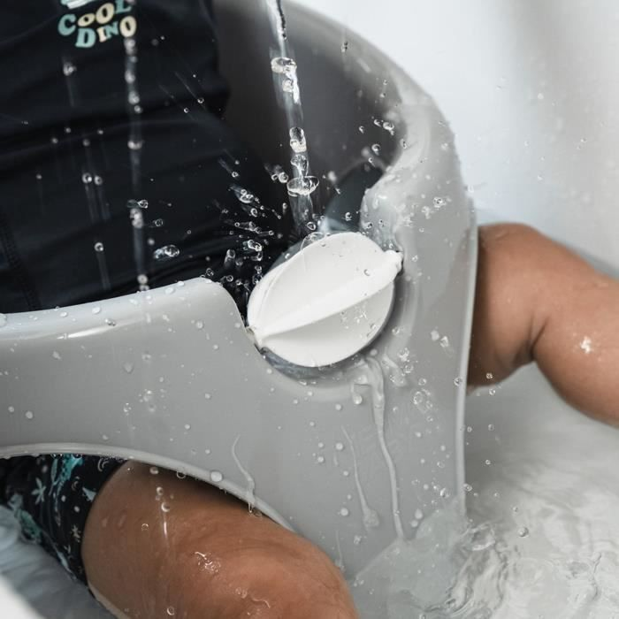 El agua cae en una bañera gris donde se sienta un niño en bañador.