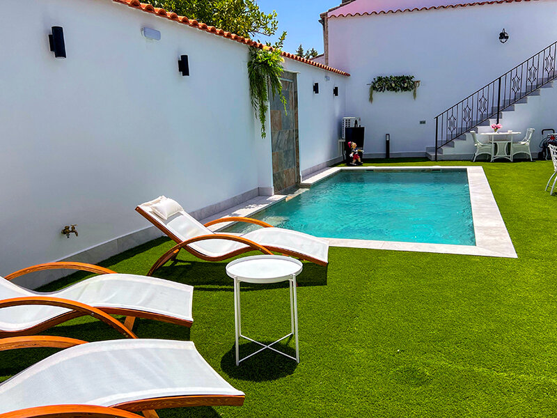 Una piscina pequeña con tumbonas y una mesa al aire libre.