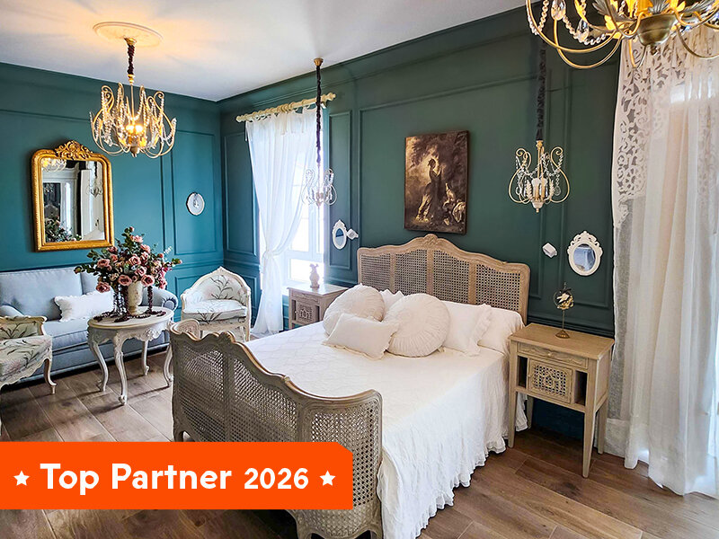 Un dormitorio con cama con dosel, sofá y espejo contra una pared verde oscuro.