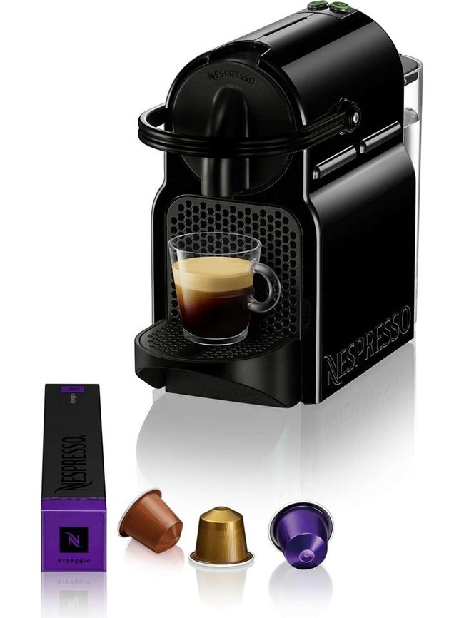 Yanında bir fincan kahve ve üç kapsül bulunan siyah Nespresso makinesi.