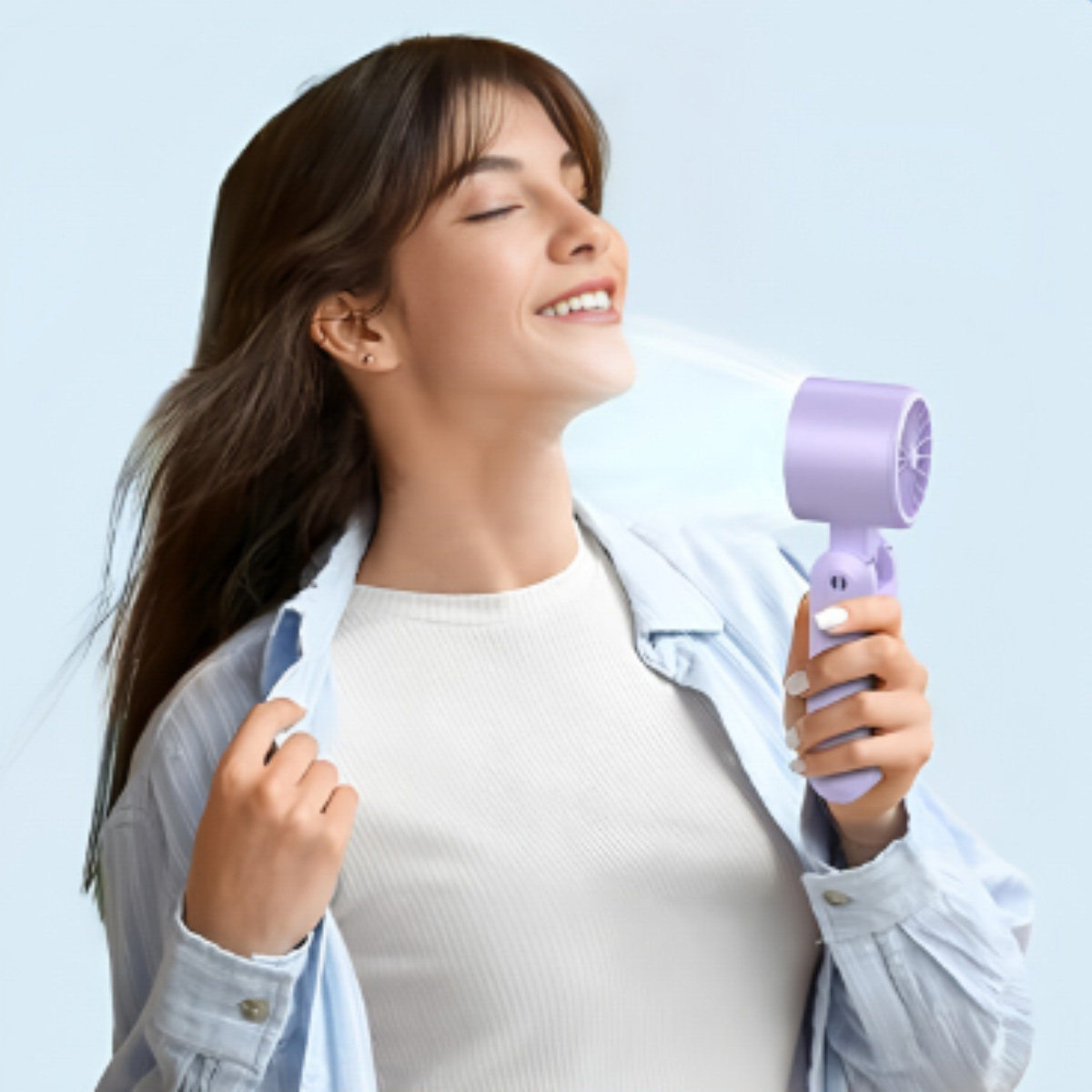 Eine Frau hält einen kleinen lila Ventilator, der kühle Luft auf ihr Gesicht bläst.