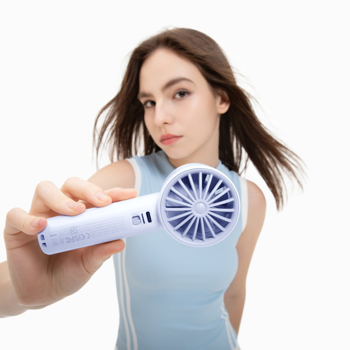 Una donna tiene in mano un ventilatore bianco portatile con rotore blu.