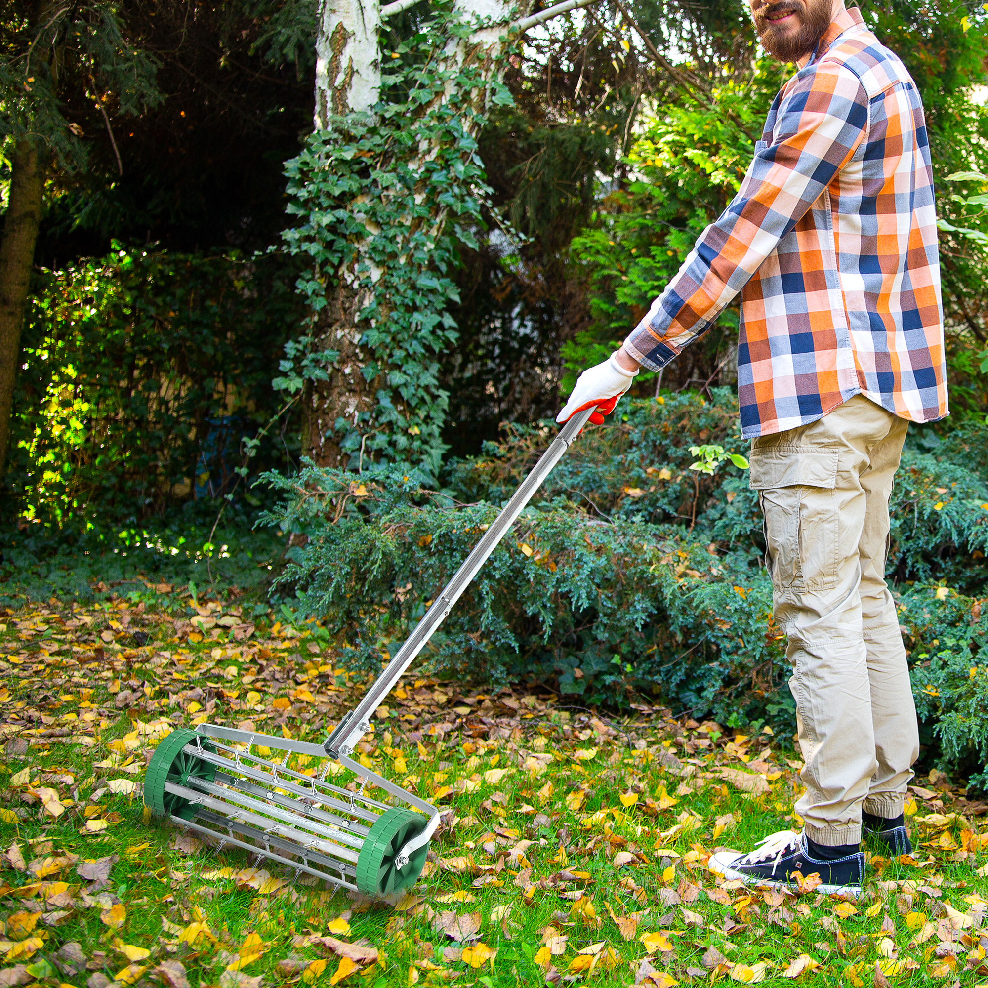 Mann mit kariertem Hemd benutzt Rasenlüfter im Herbstgarten mit Laub.