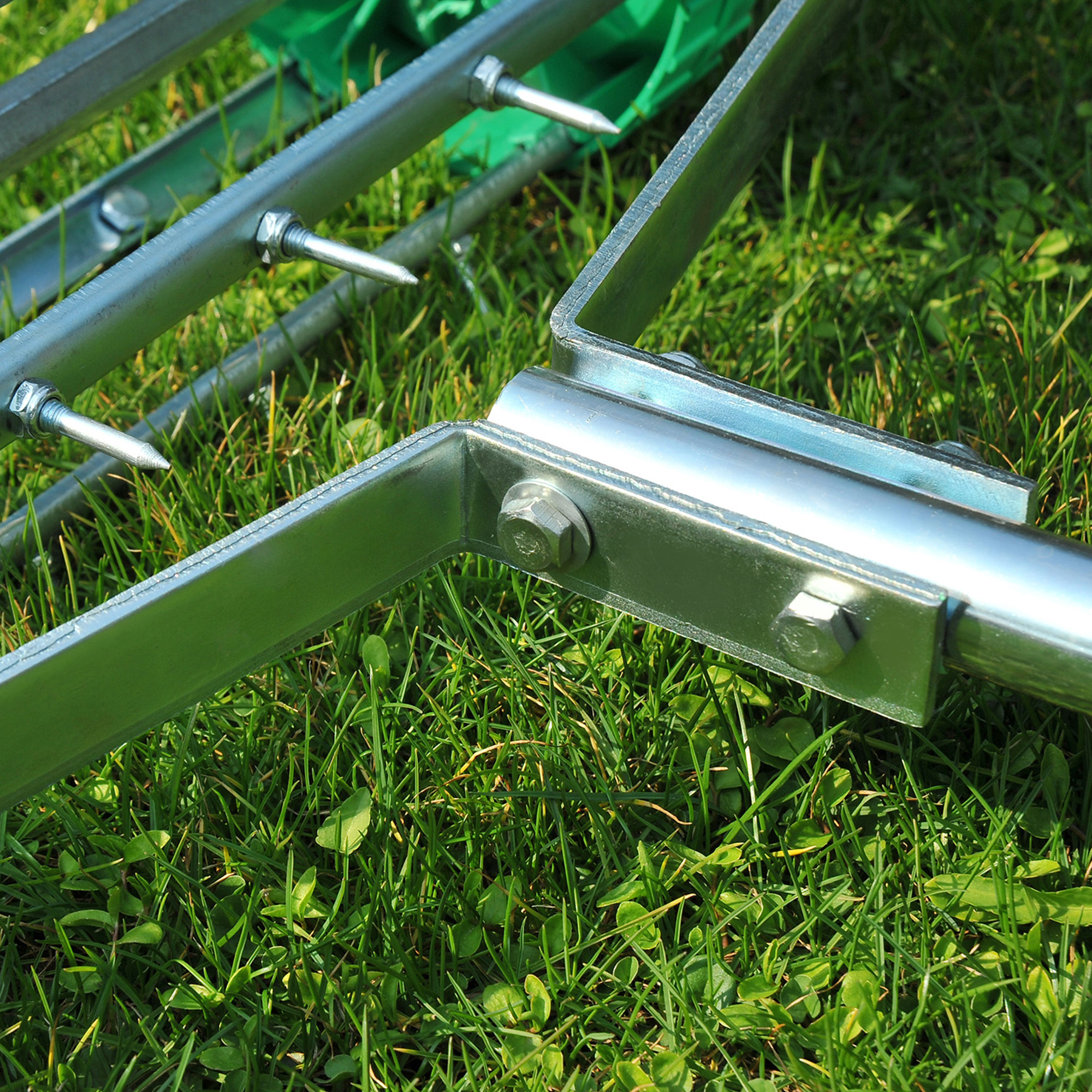 Nahaufnahme eines metallischen Rasenlüfters mit Spitzen auf grünem Gras.