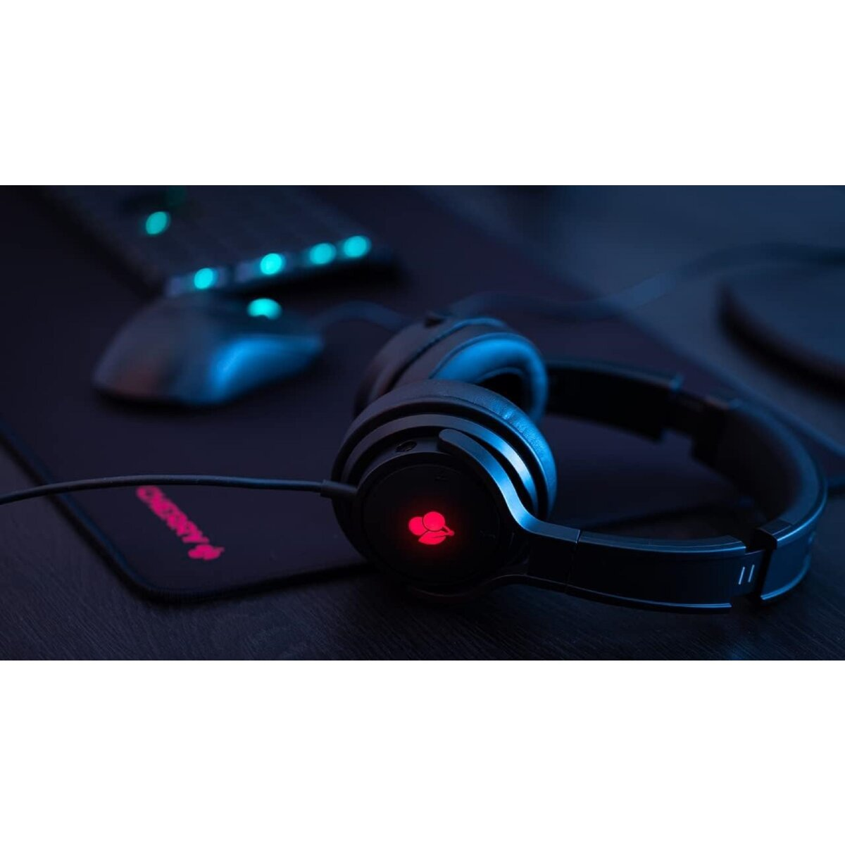 Schwarzer Gaming-Kopfhörer mit rotem Logo auf Mauspad neben Maus und Tastatur.