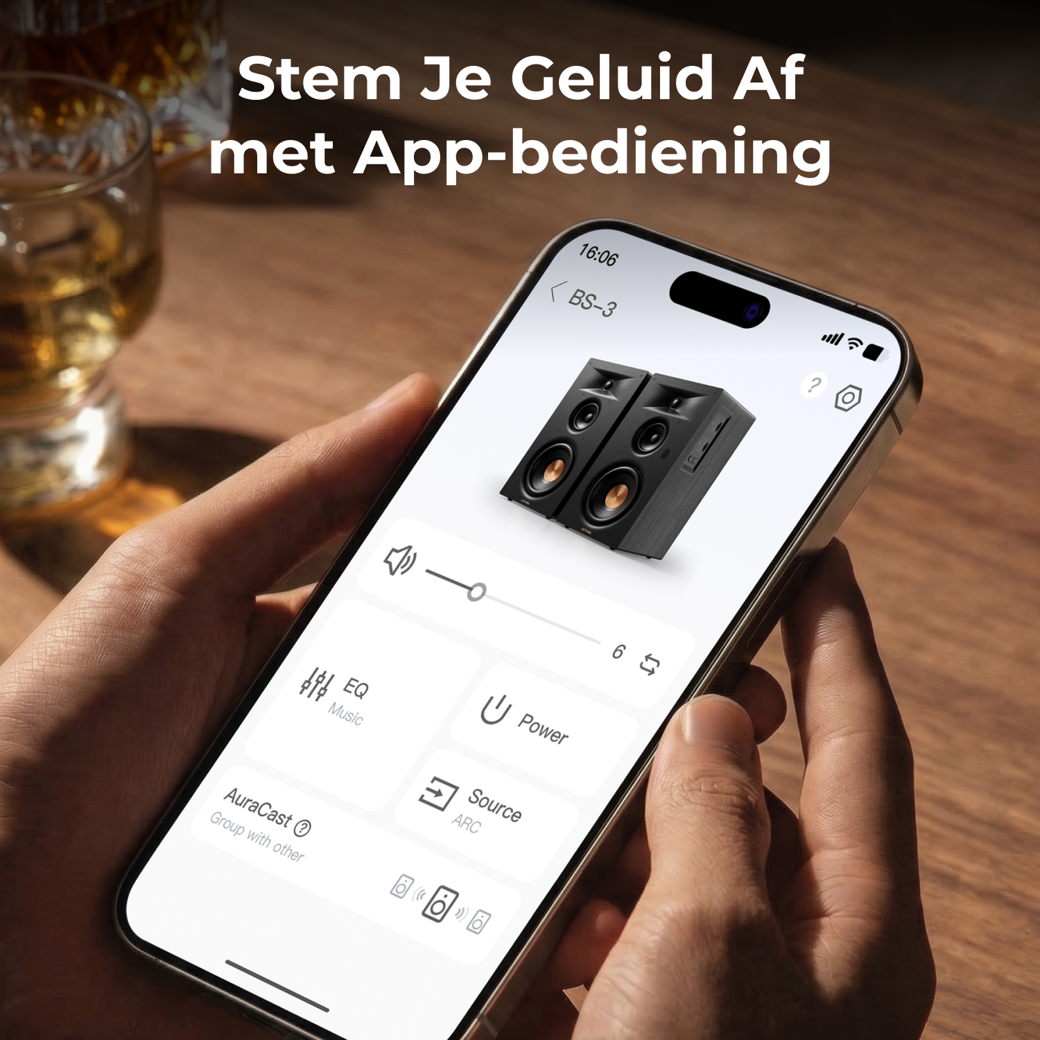 Een hand houdt een smartphone vast met een geluidsregeling-app en twee luidsprekers.