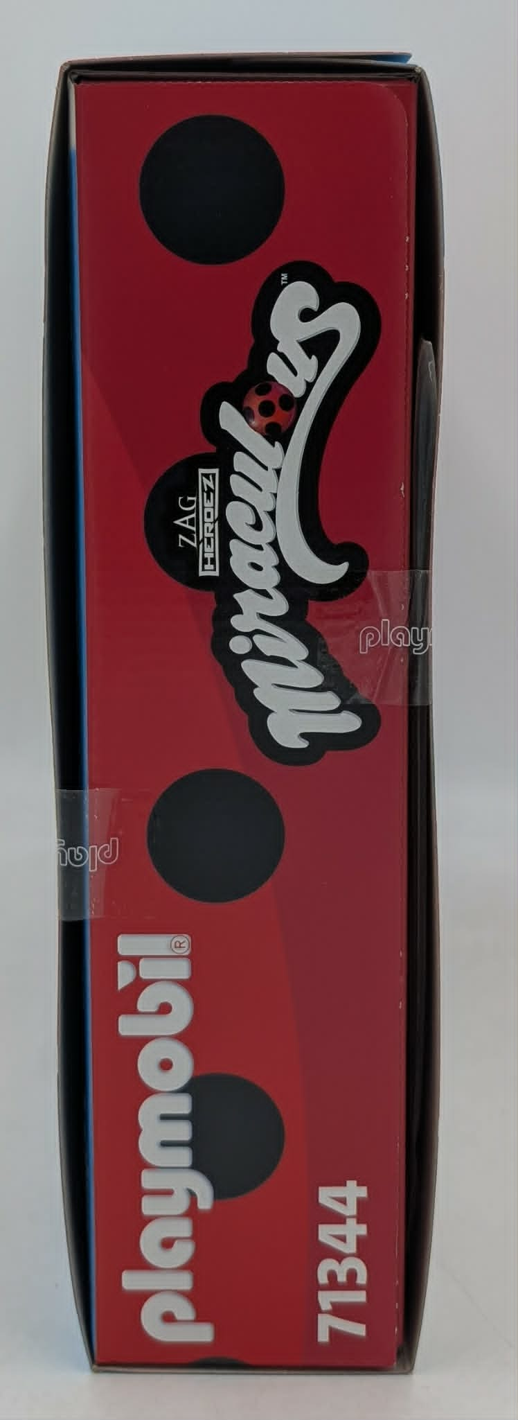 Czerwone pudełko z czarnymi kropkami i logo Miraculous.