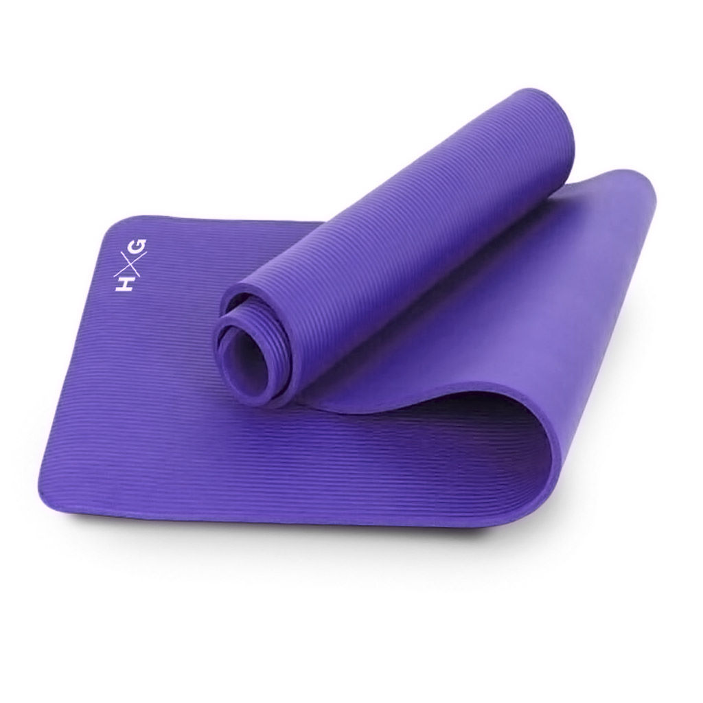 Una esterilla de yoga morada está parcialmente desenrollada, mostrando su superficie texturizada y el logo HXG.