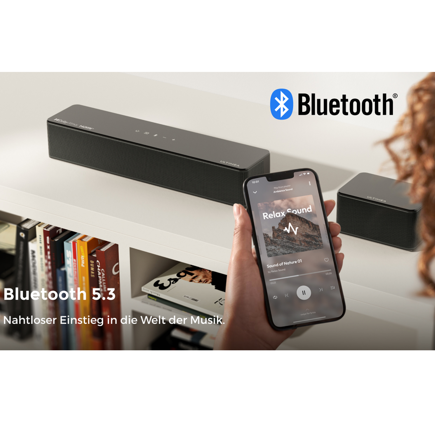 Ein Smartphone steuert eine Soundbar über Bluetooth 5.3, mit Büchern im Regal.