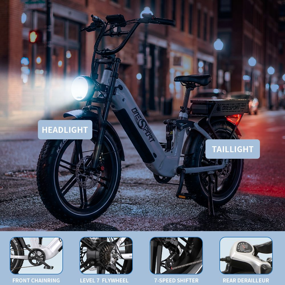 Una e-bike gris de noche con el faro y la luz trasera iluminados.