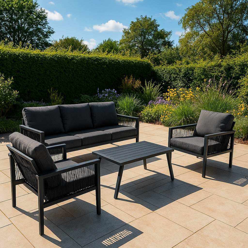 Conjunto de muebles de exterior gris oscuro en un patio con flores y arbustos.
