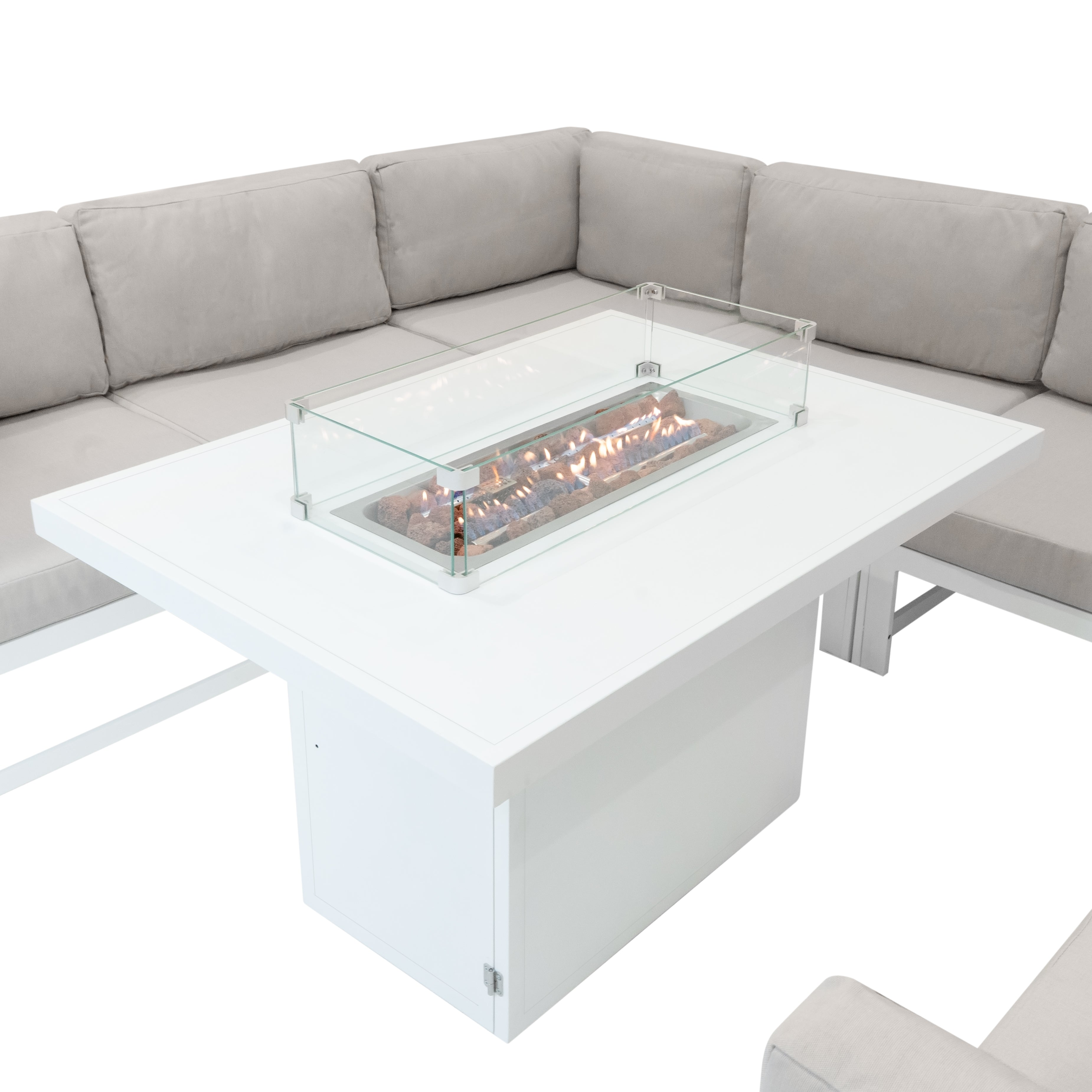 Una mesa blanca con fuego de gas integrado y rocas de lava, rodeada de cojines crema.