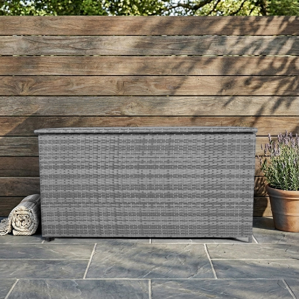 Caja de almacenamiento de ratán gris en patio de piedra frente a valla de madera.