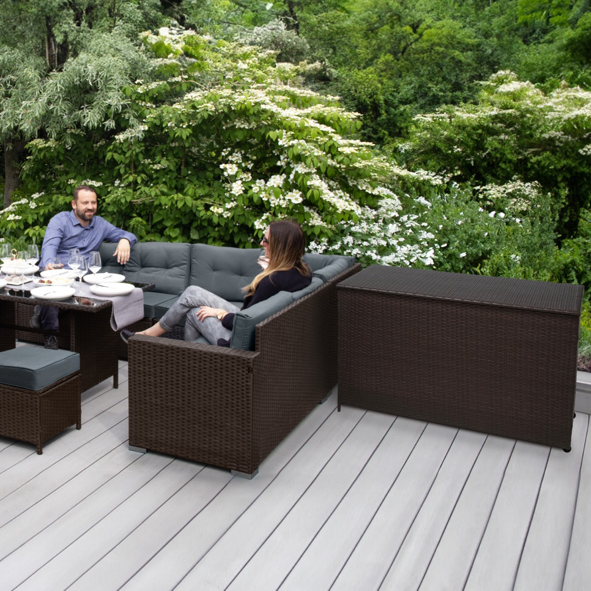 Una pareja se relaja en un sofá de jardín con mesa y baúl de almacenamiento.