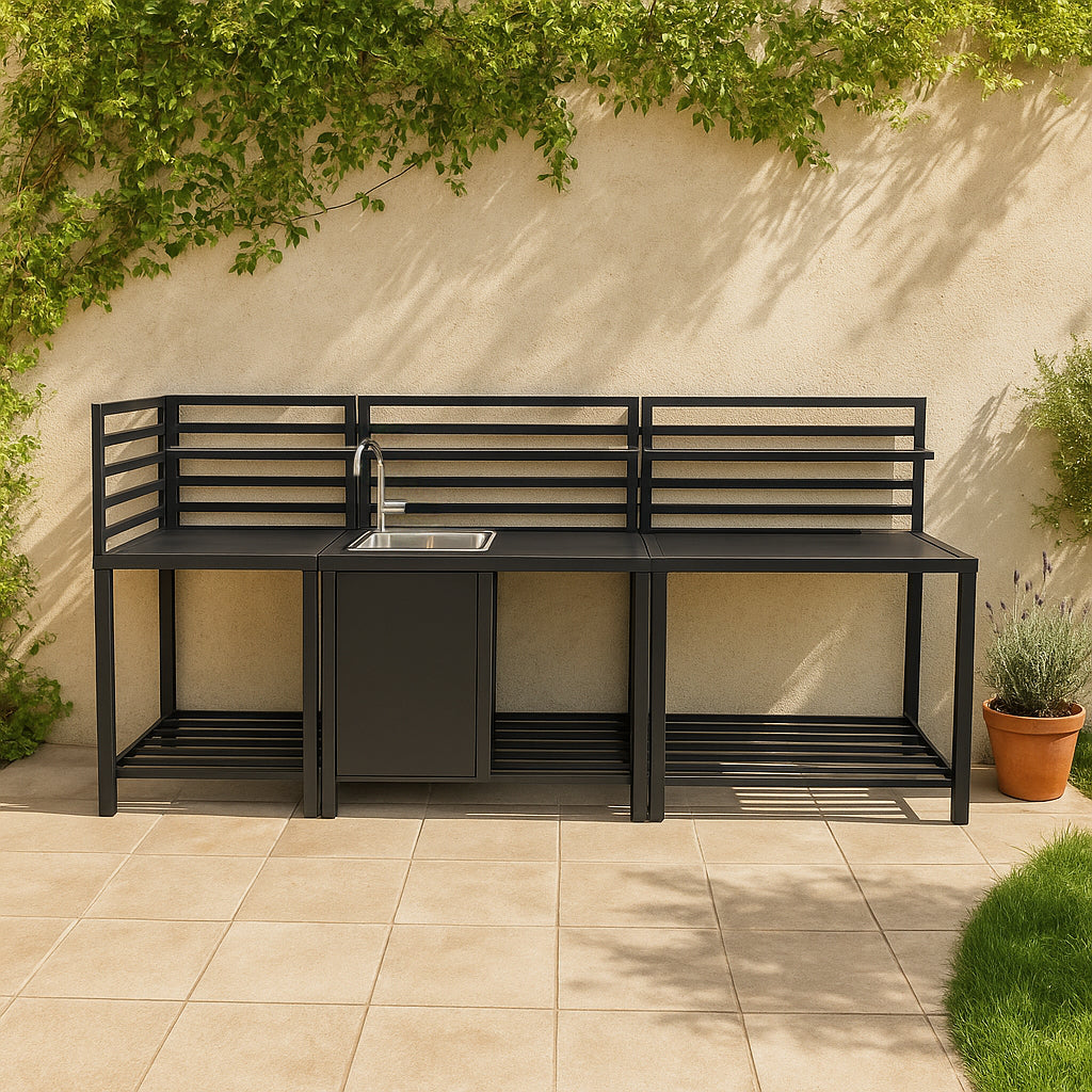 Módulo de cocina exterior negro con fregadero, almacenamiento y enredaderas en una pared.