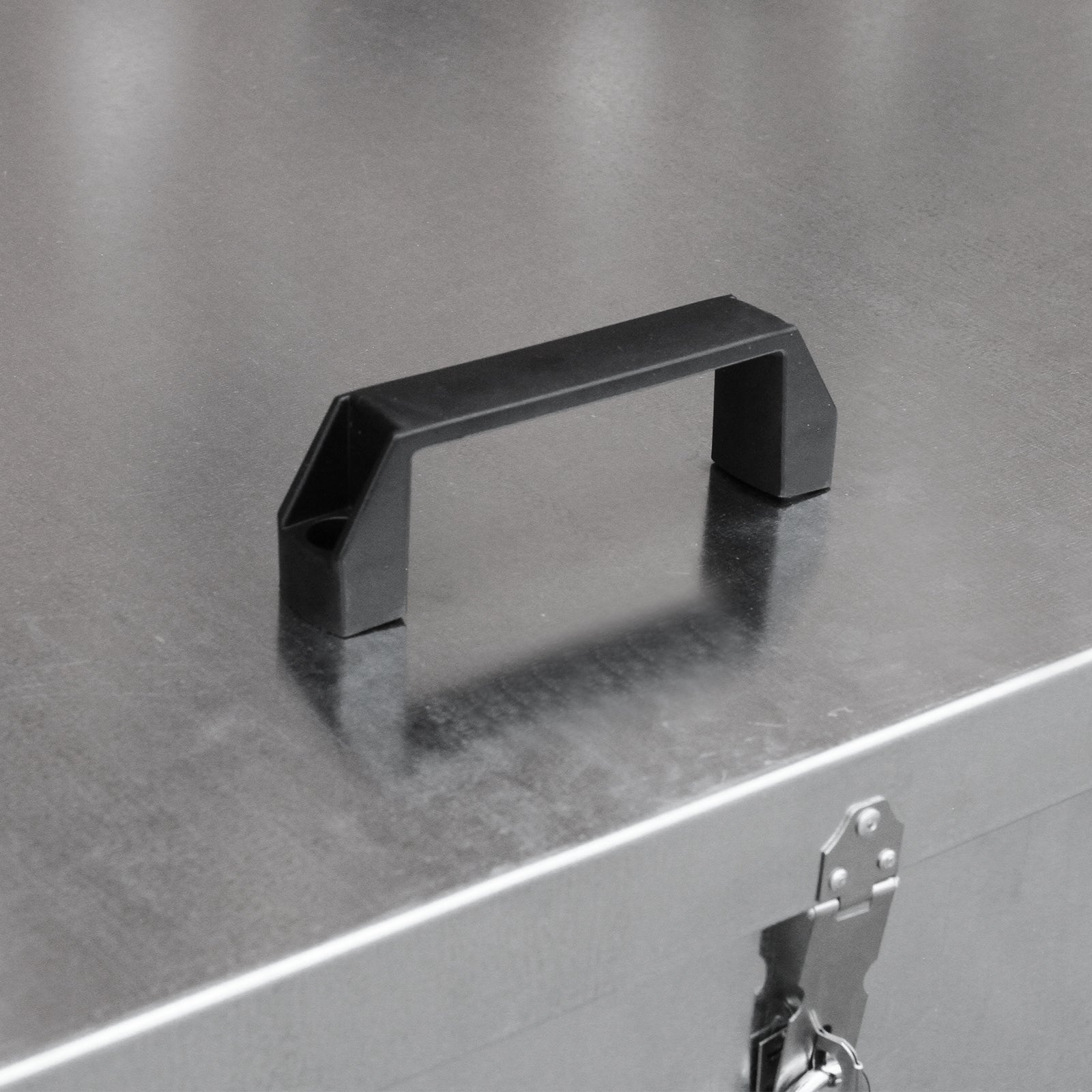 Un asa de plástico negro unida a una superficie de metal cepillado.