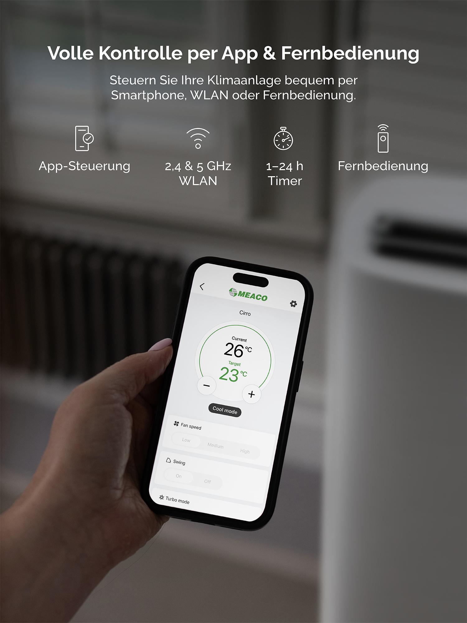 Mano sostiene smartphone con app AC: 26°C actual, 23°C objetivo.